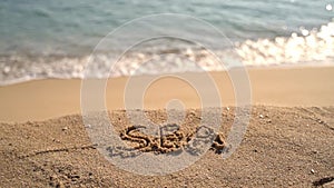 Hand written text sea on the beach. slow motion