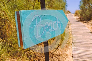 Hand written wooden sign pointing to the beach