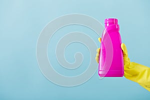 Hand in yellow glove holds a bottle of bleach on white background. cleaning