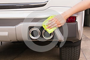 Hand with yellow microfiber cloth cleaning big white taillight c