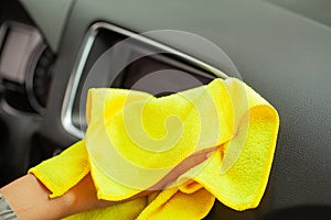 Hand with yellow microfiber cloth polishing car