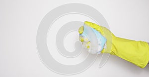 Hand in an yellow rubber glove with an blue sponge and foam on a white background. Washing dishes, cleaning, home cleaning.