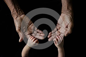 Hand of a young baby touching old hand of the elderly Soft focus and blurry