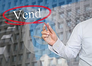 Hand of young businessman write the word Vend on skyscrapers background. photo