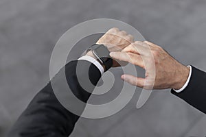 Hand of young european man in suit looks at clock, waiting for meeting at city street, cropped, close up, pov