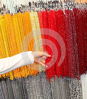 hand of a young girl while she is choosing a red glass pearl necklace photo