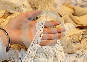 hand of a young girl lacemaker touching the fabric embroidered with laces in an tailor shop