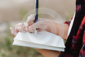 Hand of young girl writing on note book with pen