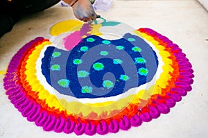 Hand of young indian girl making rangoli from colored powder on diwali eve