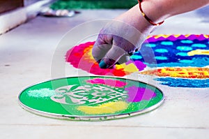 Hand of young indian girl making rangoli from colored powder on diwali eve