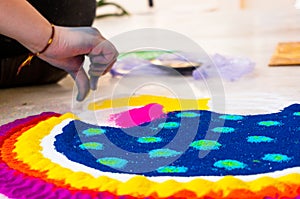 Hand of young indian girl making rangoli from colored powder on diwali eve