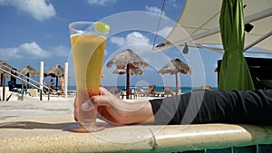 Hand of a young man with a glass of beer in the pool