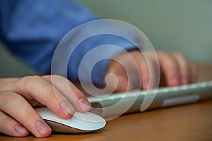 Hand of a young man on the keyboard and computer mouse close-up with depth of field