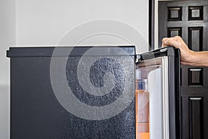 Hand of a young man is opening a freezer door in hotel