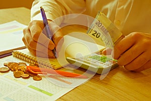 Hand of young man using calculator for calculating family budget cost bills on desk in home office, plan money cost saving,