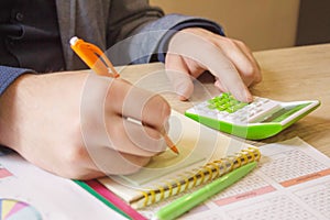 Hand of young man using calculator for calculating family budget cost bills on desk in home office, plan money cost saving,