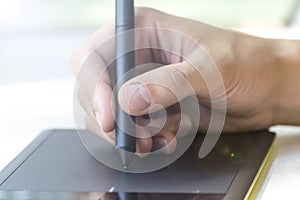 Hand of a young man writes on a graphics tablet