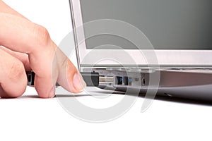 The hand of a young woman connects a USB flash drive to a port in a laptop with a black keyboard. Isolated on white background