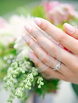 Hand of young woman with engagement ring and wedding bouquet close up.