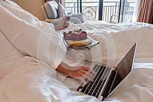 The hand of Young woman that hold wine glass And Sit play laptop In a luxurious room Ready Fruit