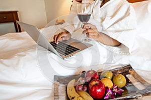 The hand of Young woman that hold wine glass And Sit play laptop In a luxurious room Ready Fruit