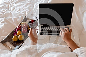 The hand of Young woman that hold wine glass And Sit play laptop In a luxurious room Ready Fruit