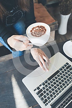 Hand Young Woman Holding a Coffee Cup and Checking her Laptop at