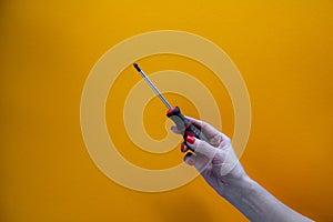 Hand of a young woman holding a screwdriverhand of a young woman holding a screwdriver, red nail polish on nails