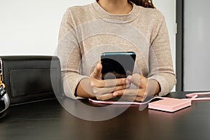 The hand of a young woman holding a smart phone and a modern Power Bank charger. Put it at the desk, charging the smartphone with