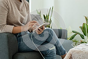 The hand of a young woman holding a smart phone and a modern Power Bank charger. Put it at the desk, charging the smartphone with