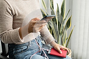 The hand of a young woman holding a smart phone and a modern spare battery charger Place the lap to charge the smartphone with a