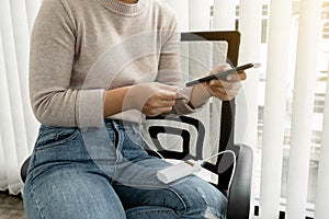 The hand of a young woman holding a smart phone and a modern spare battery charger Place the lap to charge the smartphone with a