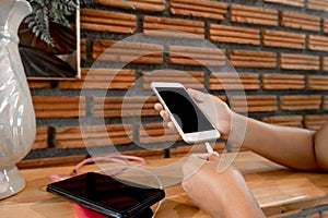 The hand of a young woman holding a smartphone and a modern spare battery charger Place the lap to charge the smartphone with a