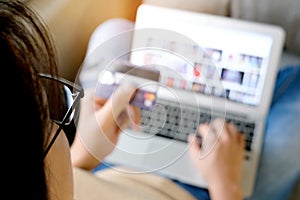 Hand of young woman  in the living room using his computer and holding credit card her online To buy product in the internet