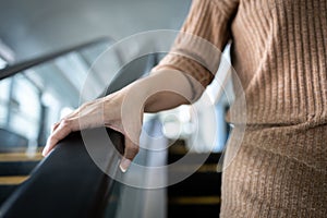 Hand of young woman touching the escalator during Coronavirus pandemic,risk of contagious or contamination of COVID-19,virus,