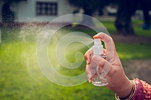 Hand of a young woman using a spray bottle outdoors