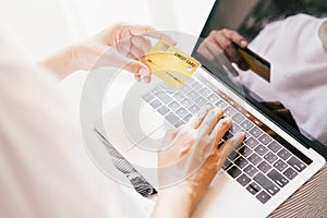 Hand of young women are buying online with a credit card. woman are using laptop and doing online transactions.