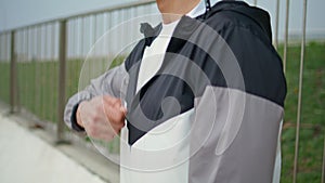 Hand zipping sport jacket on street closeup. Fitness man training in morning