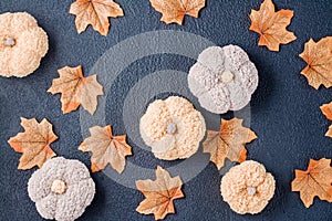 Handcraft autumn still life - knitted pumpkins and maple fabric leaves on a black background. Halloween and Thanksgiving decor.