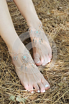 Handcrafted bracelets on a woman legs, close up, white pedicure