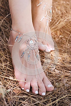 Handcrafted bracelets on a woman legs, close up, white pedicure