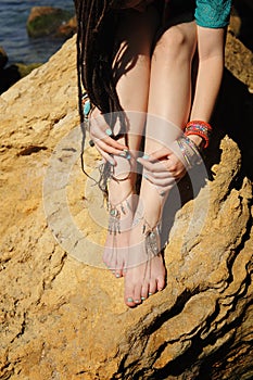 Handcrafted bracelets on a woman legs, close up, white pedicure photo