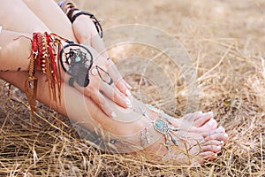 Handcrafted bracelets on a woman legs and hands, dreamcatcher jewelry