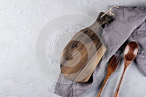 Handcrafted cutting wooden board and linen napkin on gray background. Handmade kitchenware