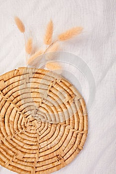 Handcrafted Wicker Coaster With Wheat Sprigs on a White Linen Background
