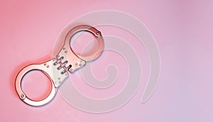 Handcuff isolated on pink banner - rape and harassment concept