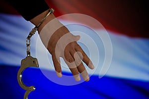 Handcuffed hand in front of the country flag. crime concept