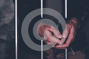 Handcuffed man behind prison bars