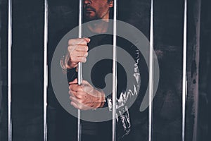 Handcuffed man behind prison bars