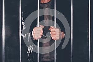 Handcuffed man behind prison bars